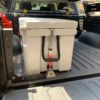 nICE 90L cooler mounted to truck bed of Toyota Tacoma truck using stainless steel IronFist base lock and StiffArm-16 locking bar.